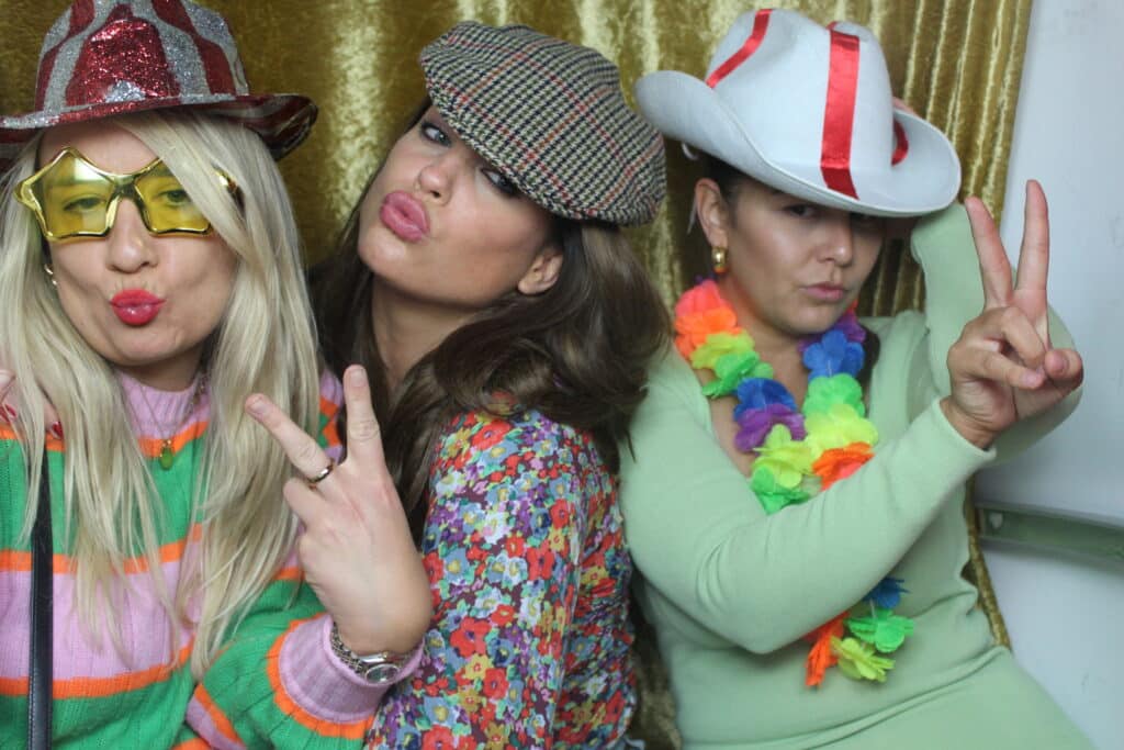 Group of women posing for a photo in front of a photo booth.