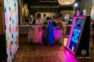 Two elegantly dressed ladies carefully selecting props for creating the perfect pictures in a photo booth.