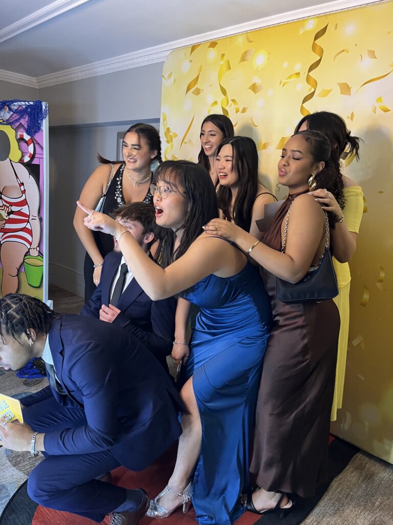 Group of people posing and smiling in front of a photo booth at a party.