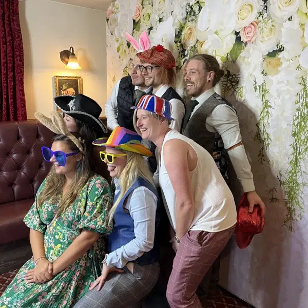Group of friends posing in photo booth with funky props