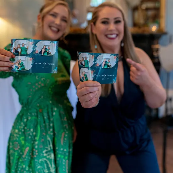 Wedding guests showing off their printed photo booth strips