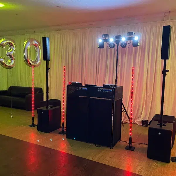 Modern DJ setup with column speakers and red uplighting for a 30th birthday in Crawley