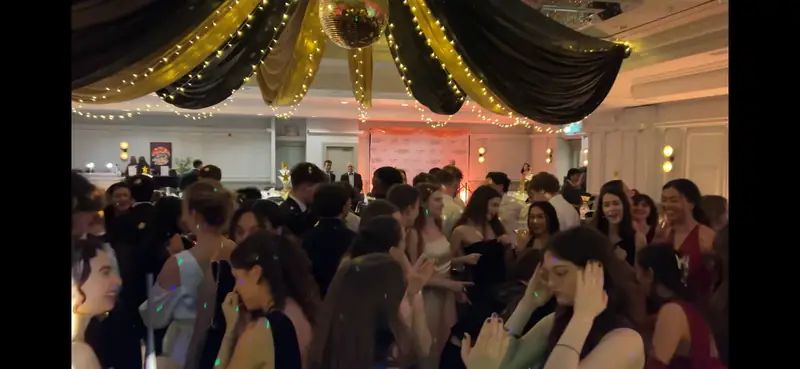 Packed prom dancefloor in Crawley under gold drapes and fairy lights