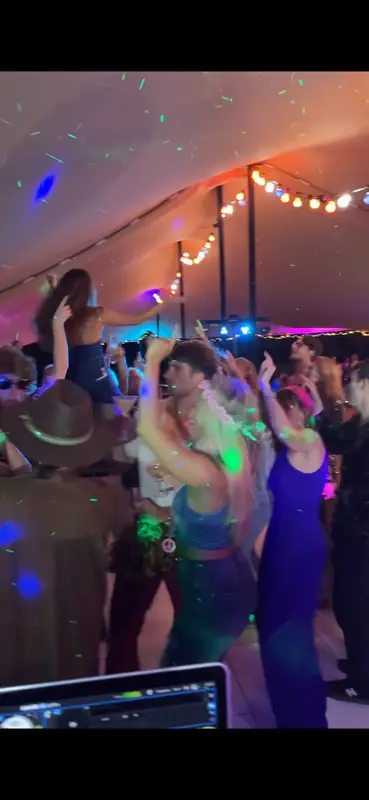 Outdoor tent party in Sussex – view from the DJ booth with guests dancing under festoon lights