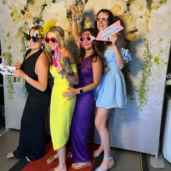 Group of guests at flower wall photo booth having fun