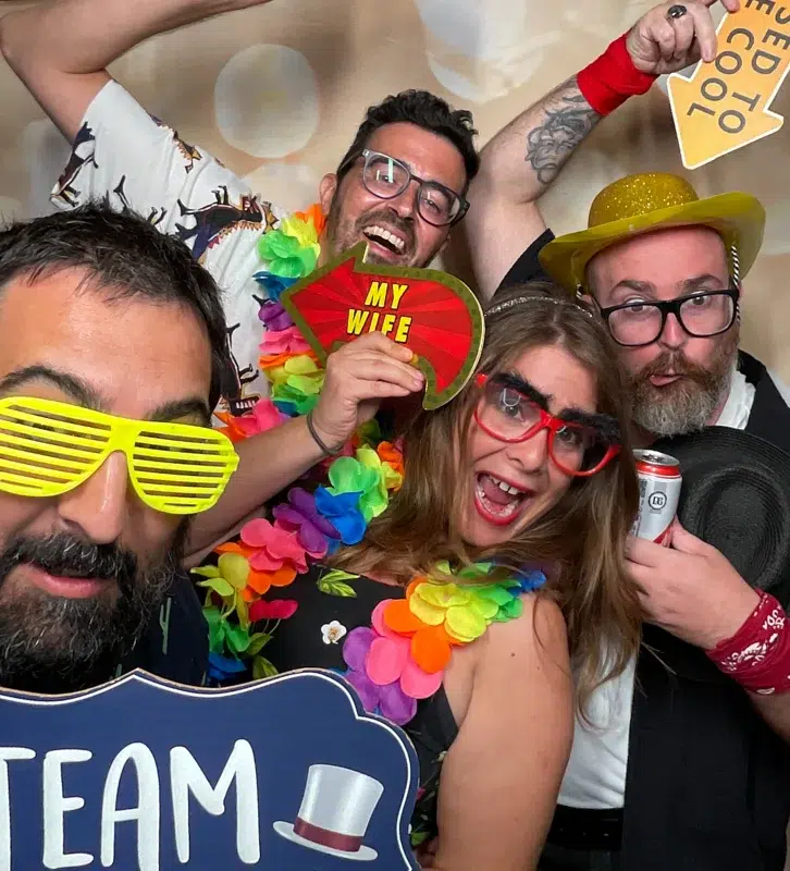 Guests having fun at a Guildford wedding photo booth with colourful props and big smiles