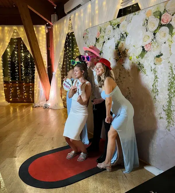 Wedding guests using colourful props at photo booth